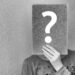 A person looking at a wall with many question marks
