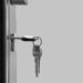 Black and white image of a set of keys and one turned horizontally in a lock